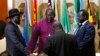 FILE - South Sudan's rebel leader Riek Machar (R) and South Sudan's President Salva Kiir (L) hold a priest's hands before signing an earlier peace agreement in Addis Ababa May 9, 2014.