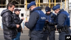 Des policiers vérifient les passeports de deux hommes alors qu'ils essaient de traverser la frontière franco-belge à Adinkerke, en Belgique, le mercredi 24 février 2016.