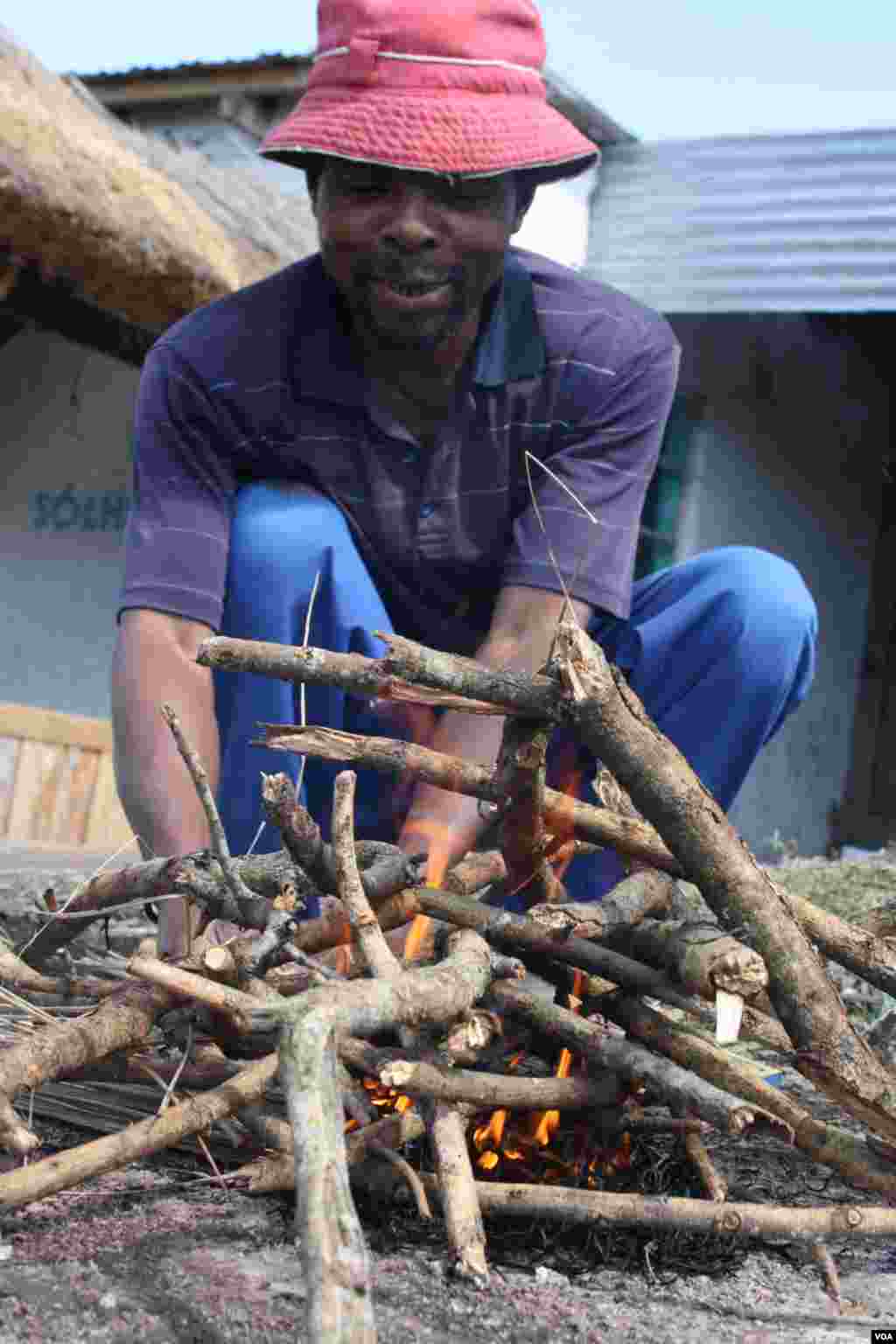Sisa’s companion at the home, Patekile Mofeti, lights a fire for a barbecue (VOA/ D. Taylor) 