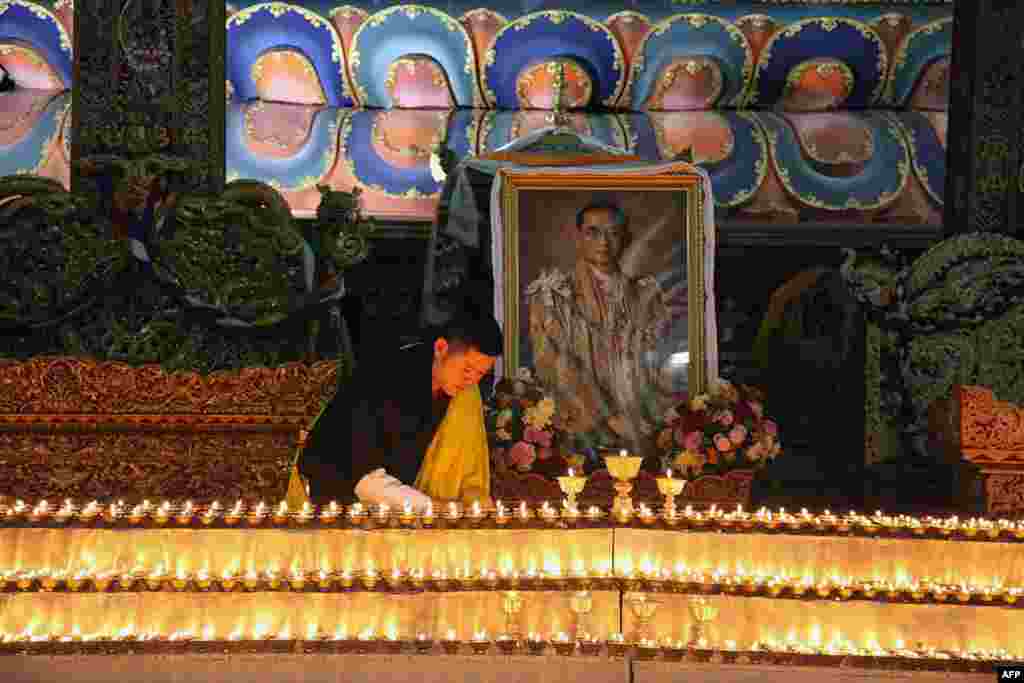 This photograph released by Bhutan&#39;s Royal Office for Media shows King Jigme Khesar lighting candles at the Kuenra of the Tashichhodzong in Thimpu next to a portrait of Thailand's King Bhumibol Adulyadej, who died in Bangkok.