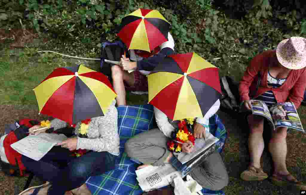 Para wisatawan istirahat di komplek All England tempat berlangsungnya pertandingan tennis Wimbledon di London.