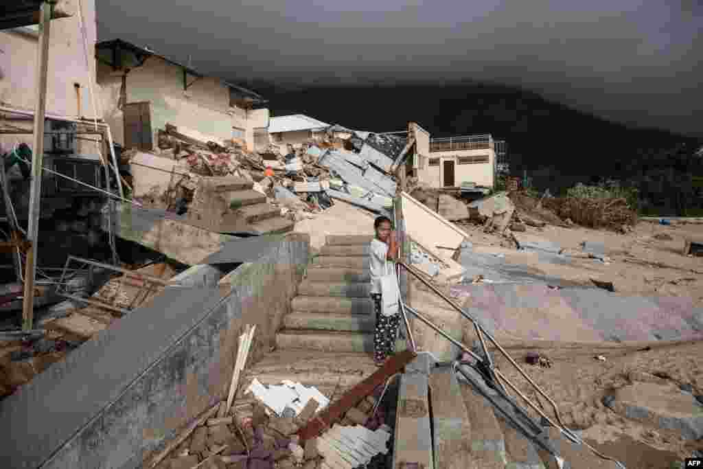 ស្រ្តី​ម្នាក់​ឈរ​នៅ​មុខ​សាលារៀន​ដែល​បាន​ខូចខាត​បន្ទាប់​ពី​មាន​ព្យុះ​សង្ឃរា&nbsp;Mangkhut នៅ​ភូមិ​Shek&nbsp;O&nbsp;កោះ​ហុងកុង។