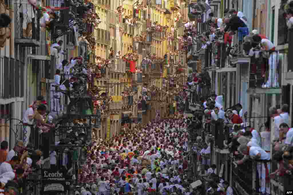 Orang-orang berdiri di balkon di depan Alcurrucen untuk menyaksikan peserta adu kejar banteng di Festival San Fermin di Pamplona, Spanyol utara, 7 Juli 2013. 
