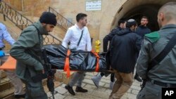 Israeli security personnel and members of Zaka Rescue and Recovery team carry the body of a Palestinian man who was fatally shot by Israeli police after he killed one Israeli and wounded four others in a shooting attack in Jerusalem's Old City, Sunday, No