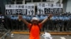 A protester holds up placards which reads "Occupy Central" (L) and "Civil Disobedience" in front of a line of riot police outside government headquarters in Hong Kong, Sept. 27, 2014. 