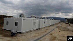 一名工人走过西维市的一排集装箱式住房，西维市位于雅典以北大约90公里处。这座旧纺织厂将在几天后开放给700名难民和移民居住（2017年3月14日图片）