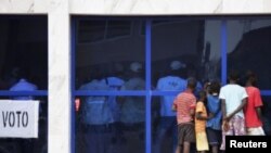 Wasu yara su na kallon jami'an zabe su na kidaya kuri'u ta gilashin ginin hukumar a Bissau, babban birnin kasar Guinea-Bissau, Lahadi 18 Maris, 2012. 