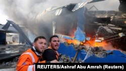 Wazima moto Wapalestina wakijitahidi kuuzima moto katika kiwanda cha magodoro baada ya kupigwa na mabomu yaliyorushwa na kikosi cha mizinga cha Israeli huko Gaza Mei 17, 2021.REUTERS/Ashraf Abu Amrah