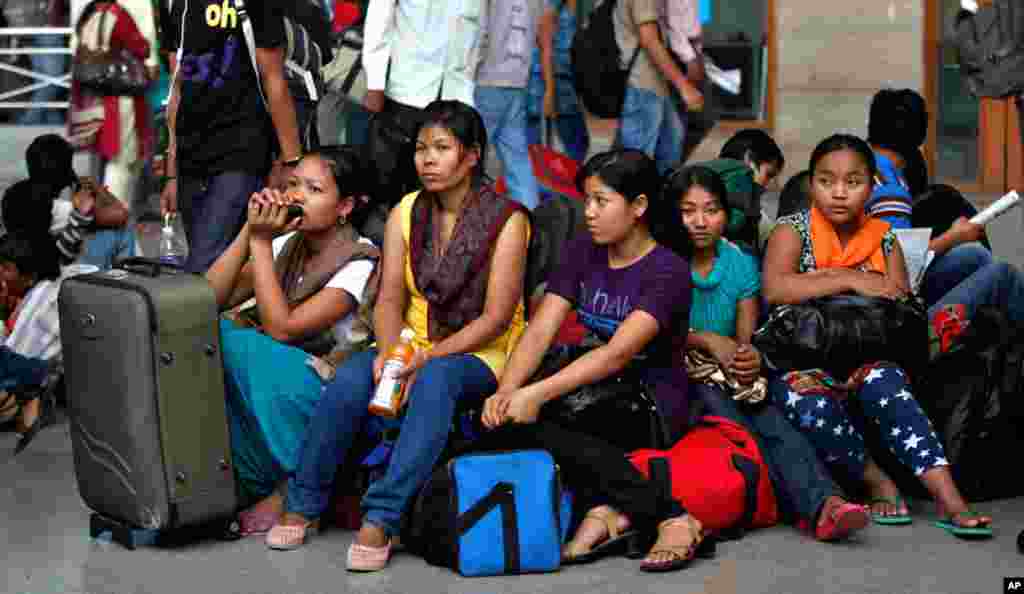 Women wait with their baggage to board trains home in Bangalore.