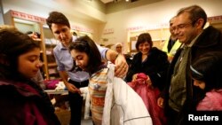 Le Premier ministre du Canada Justin Trudeau aide un jeune réfugié syrien à essayer un manteau d'hiver après son arrivée avec sa famille de Beyrouth à l'aéroport international Pearson de Toronto à Mississauga , Ontario, Canada 11 décembre 2015.