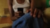 Seventeen year-old sex worker checks email on his mobile phone, Mombasa, Kenya, July 21, 2012 (VOA/Jill Craig).