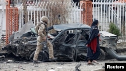 资料照片：阿富汗安全部队成员检查喀布尔一处爆炸现场被炸毁的汽车。(2020年12月20日) 