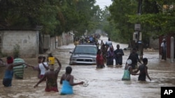 Warga Port-au-Prince, Haiti, mengarungi genangan banjir yang dipicu badai tropis Isaac. (Foto: AP/Dieu Nalio Chery)