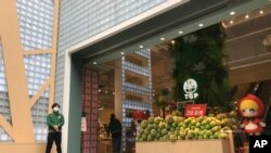 A store employee waits outside for customers at a re-opened retail street in Wuhan in central China's Hubei province on Monday, March 30, 2020. Shopkeepers in the city at the center of China's virus outbreak were reopening Monday but customers were…