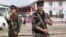 This photo taken on July 28, 2016 shows two Myanmar armed rebels from the Kachin Independence Army (KIA) securing the compound (behind) where Myanmar ethnic rebel leaders and representatives have gathered for a four-day summit in Mai Ja Yang, the KIA cont