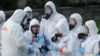 Workers from a Servpro disaster recovery team wearing protective suits and respirators are given supplies as they line up before entering the Life Care Center in Kirkland, Wash., to begin cleaning and disinfecting the facility, Wednesday, March 11, 2020…