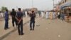 Security officers stand guard at the scene of an explosion at a mobile phone market in Kano, Nigeria. Wednesday Nov. 18, 2015. 