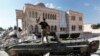 FILE - A Free Syrian Army soldier stands on a Syrian military tank in front of a mosque, which were damaged during fighting with government forces, in the Syrian town of Azaz, on the outskirts of Aleppo, Sept. 23, 2012.