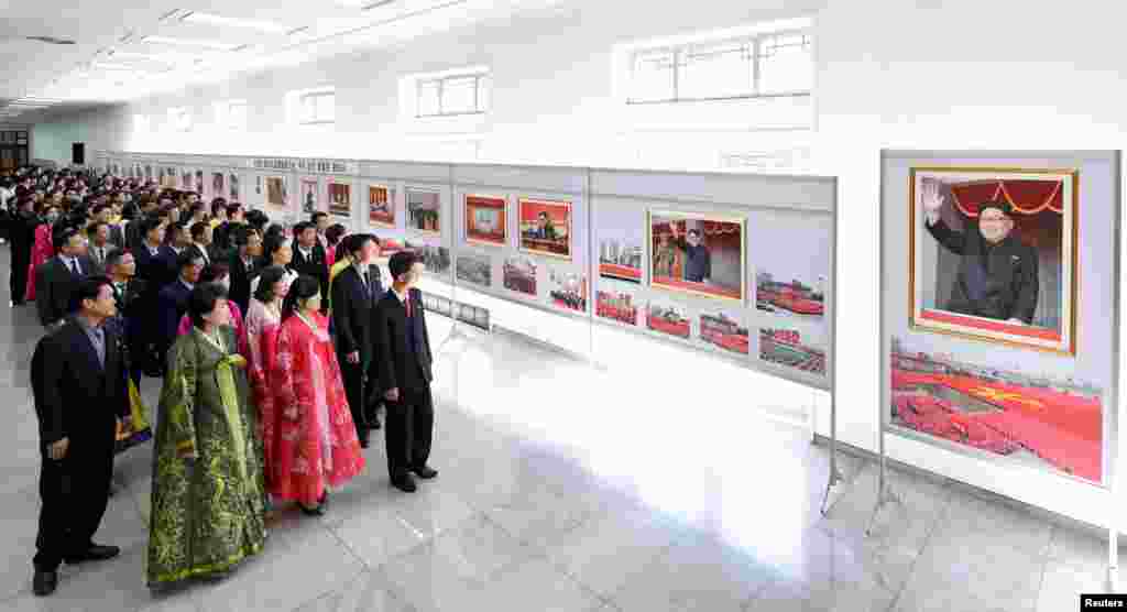 ទស្សនិក​ជន​កំពុង​មើល​រូបថត​មួយ​ដែល​ត្រូវ​បាន​គេ​ដាក់តាំង​នៅ​ក្នុង​ការ​តាំង​ពិរព័ណ៌​មួយ​អបអរការ​ជាប់ឆ្នោត​របស់​លោក​គីម ជុង​អ៊ីល​ជា​អគ្គ​លេខាធិការ​របស់​គណបក្ស​ Workers&#39; Party of Korea​ នៅ​ក្នុង​វិមាន​វប្បធម៌​ប្រជាជន​។