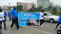 Two participants hold banner during ability awareness march, July 29, 2021. (Timothy Obiezu/VOA)