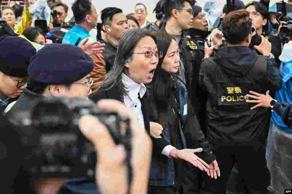 Police detain a woman (C) outside the West Kowloon Magistrates&#39; Court in Hong Kong.Hong Kong&#39;s largest national security trial will draw to a close with dozens of the city&#39;s most prominent democracy campaigners set to be sentenced for subversion, a charge which can carry up to life imprisonment.