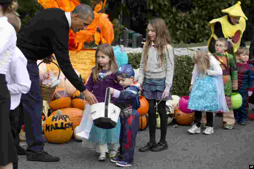 2014年10月31日，奥巴马总统夫妇在白宫给来自首都华盛顿地区的身穿各种万圣夜服装的孩子们分发糖果。