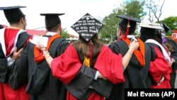 FILE - In this May 15, 2016 file photo, students embrace as they arrive for the Rutgers graduation ceremonies in Piscataway, New Jersey. (AP Photo/Mel Evans)