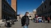 A man wearing a protective mask walks through an empty Saint Mark's Square in Venice as Italy battles a coronavirus outbreak, Venice, Feb. 27, 2020.