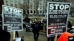 Des manifestants tiennent des panneaux de protestation contre le président élu au McPherson Square, à Washington, le 14 janvier 2017. 