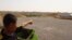 Faisel, 13, points at his house on the other side of the barbed-wire fence surrounding the camp, May 29, 2018, in Hassan Sham, Iraqi Kurdistan. (H. Murdock/VOA)