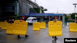 武汉火车站前工人搬走为防疫设置的路障。（2020年3月28日）