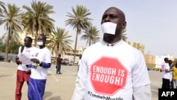 Des manifestants ont couvert leur bouche avec du papier et portent un t-shirt sur lequel il est marqué "assez c'est assez" à Dakar le 22 avril 2016, contre les violations des droits de l'homme en Gambie.