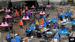 FILE - Maricopa county ballots cast in the 2020 election are examined and recounted by contractors working for Florida-based company Cyber Ninjas at Veterans Memorial Coliseum in Phoenix, Arizona, May 6, 2021.