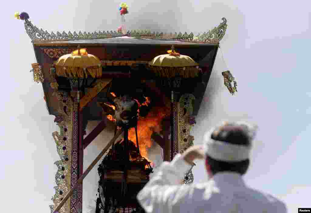 A man watches the cremation of Ida Anak Agung Ayu Oka Pemecutan, a member of the Denpasar royal family, during a Hindu Ngaben, or cremation ceremony, in Denpasar, Bali, Indonesia.