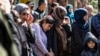 FILE - Iraqi Yazidi women and children rescued from the Islamic State group wait to board buses bound for Sinjar in Iraq's Yazidi heartland, April 13, 2019.