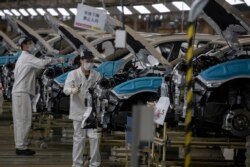 工人们佩戴口罩在位于湖北省武汉市的汽车装配线上工作。（2020年4月8日）