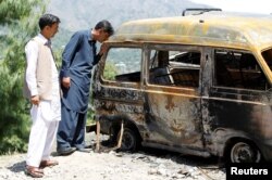 People look at the van in which Ambreen Riasat was burned in the village of Makol outside Abbottabad, Pakistan, May 6, 2016.