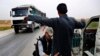 In this March 28, 2018 photo, a Kurdish policeman checks an Arab Syrian man at a checkpoint controlled by The U.S.-backed Syrian Democratic Forces, SDF, on a highway in Hassakeh province.
