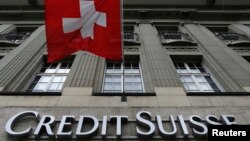 Logo bank milik Swiss, Credit Suisse, tampak di bawah bendera Swiss di sebuah gedung yang terletak di Federal Square di Bern, 15 May 2014 (foto: Reuters/Ruben Sprich)