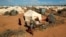 FILE - Refugees stand outside their tent at the Dadaab camp near the Kenya-Somalia border, Oct. 19, 2011. The Dadaab camp has hosted hundreds of thousands of Somali refugees for decades.