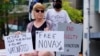A protestor holds signs outside the Park Hotel, where Serbian tennis player Novak Djokovic is believed to be held, in Melbourne, Australia January 6, 2022. 