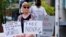 A protestor holds signs outside the Park Hotel, where Serbian tennis player Novak Djokovic is believed to be held, in Melbourne, Australia January 6, 2022. 