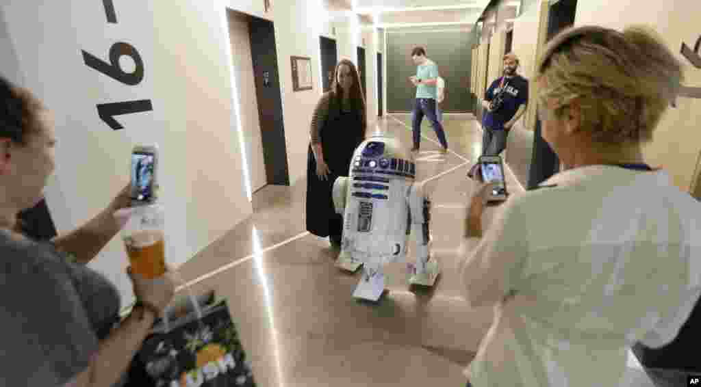 在西雅图的一座大楼里，影片《星球大战》里的机器人R2D2 和工作人员互动（2017年5月4日）。在6月下旬的拍卖中，这个机器人可能卖到200万美元。《星球大战》的一些道具也会拍卖，男主角用过的光剑可能卖到15万到25万美元。