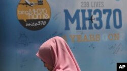 মালয়েশিয়ার রাজধানী কুয়ালা লামপুরে এমএইচ ৩৭০ স্মরণে একটি বোর্ডের পাশে একজন দাঁড়িয়ে আছেন। ফটোঃ ৩ মার্চ, ২০২৪।