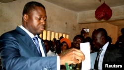 FILE - President of Togo Faure Gnassingbe (L) casts his ballot inside a school in Lome, Jul. 25, 2013.