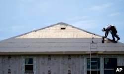 FILE -- A construction worker puts down roofing paper on a new home in Houston. Texas was a popular destination for new home buyers in 2018.