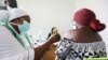 FILE - A medical worker injects the AstraZeneca's COVID-19 vaccine into a woman at the National Hospital in Abuja, Nigeria, March 31, 2021. 