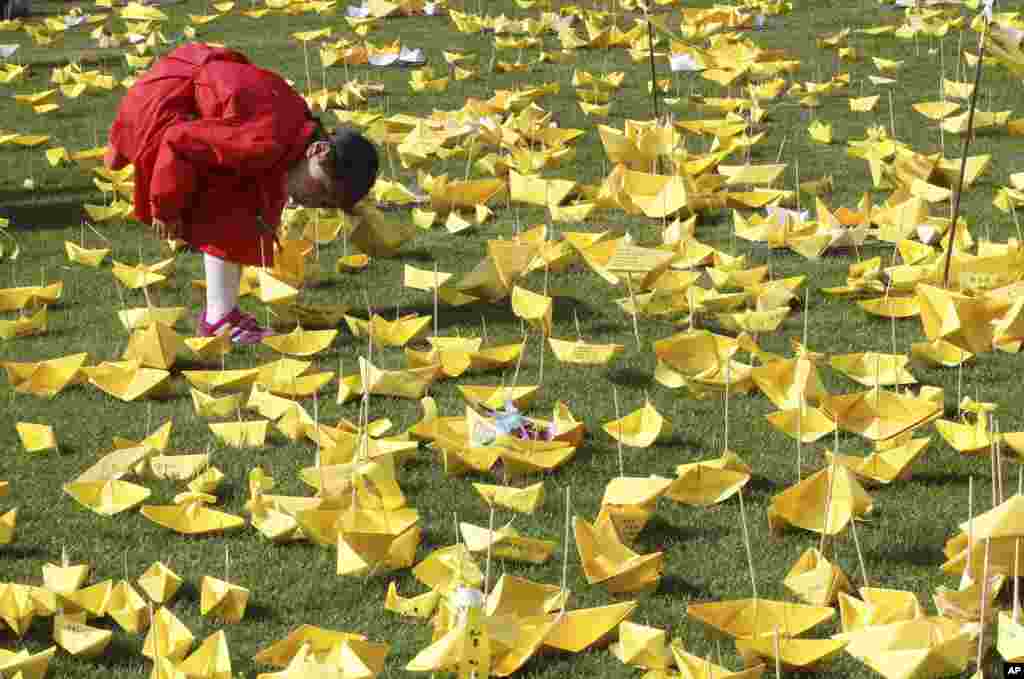 Seorang anak perempuan membaca pesan-pesan pada kapal kertas yang ditulis untuk para korban kapal feri Sewol di dekat tugu peringatan di Seoul, Korea Selatan.