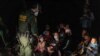 Asylum-seeking migrant families sit on the ground as an U.S. Border Patrol agent checks on them after crossing the Rio Grande river into the United States from Mexico in Roma, Texas, Aug. 14, 2021. 
