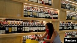 FILE PHOTO: A woman wearing a protective mask lines up outside a liquour shop after Bangkok and several other provinces announced a 10-day ban on alcohol sale starting April 10 during the coronavirus disease (COVID-19) outbreak in Bangkok, Thailand,…
